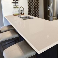 a kitchen counter with two stools next to it and a refrigerator in the background