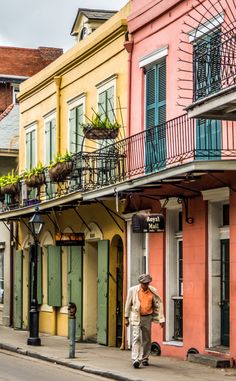 a man walking down the street in front of some colorful buildings with balconies