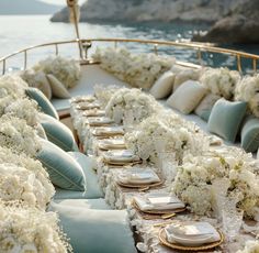 the table is set up with white flowers and place settings for dinner on the boat