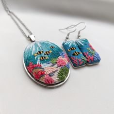 two necklaces with colorful designs on them sitting on a white surface next to each other