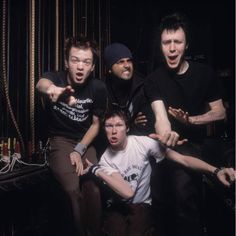 four men are posing for a photo in front of ropes and wires, with one pointing at the camera