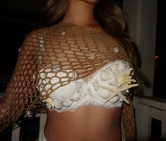 a woman wearing a white bra with shells on it's chest and undershirt