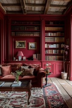 a living room with red walls and lots of bookshelves in it's center