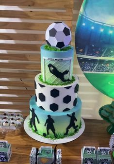 there is a cake with soccer themed decorations on the top and bottom tier, along with other desserts