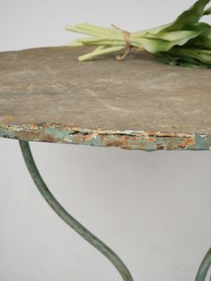 a close up of a metal table with flowers on it and a white wall in the background