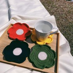 four crocheted coasters on a wooden tray with a cup and saucer