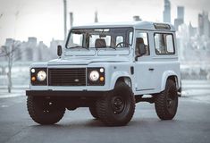 a white land rover vehicle parked in front of a cityscape with skyscrapers