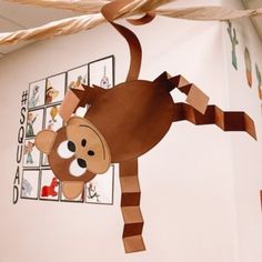 a paper monkey hanging from the ceiling in a child's playroom with pictures on the wall