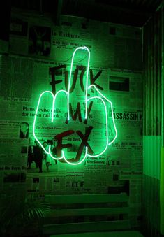 a green neon sign with the word fix on it in front of a newspaper wall