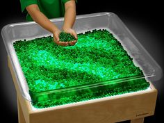 a young boy standing in front of a green cake