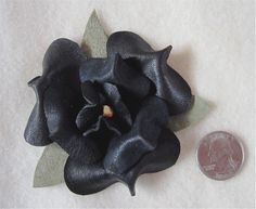 a small black flower sitting next to a penny