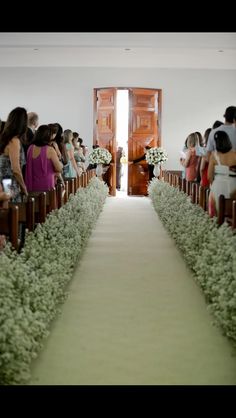 a group of people standing at the end of a church aisle with flowers in front of them