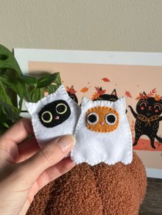 two small stuffed animals sitting on top of a potted plant in front of a wall