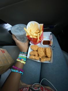 a person sitting in the back seat of a car eating french fries and ketchup