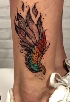 a woman's foot with a colorful tattoo on the side of her leg and an eagle