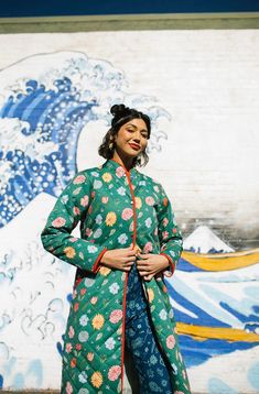 "The Beijing Quilted Coat is a classic staple for your wardrobe. The fit is a mix of a vintage coat pattern and the traditional Hanfu Chinese design. It is printed in two color-ways- a batik-inspired blue floral (a wax resist technique used across Asia) and green which has a contrasting pop of red piping and a multi-color floral pattern all over. The blue floral has an adorable light blue pinstripe lining that can be seen when you fold the cuffs. The green has a light sage green varied stripe li Luxury Green Quilted Jacket, Luxury Green Long Sleeve Quilted Jacket, Parker Coat, Quilted Coats, Crushed Velvet Fabric, Patchwork Coat, Floral Vests, Wax Resist, Color Ways