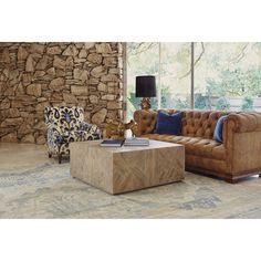 a living room with two couches and a coffee table in front of a stone wall