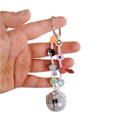 a hand holding a keychain with beads and charms on it's side