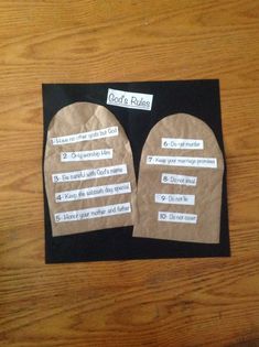 two pieces of paper with words written on them sitting on top of a wooden table