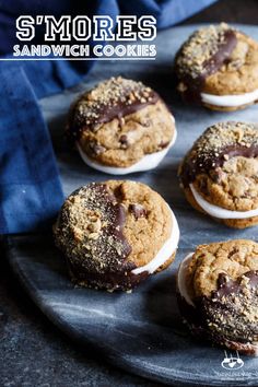 six cookies with chocolate frosting and sprinkles on a black platter