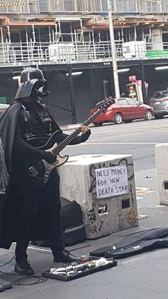 a man dressed as darth vader playing guitar on the street