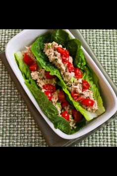 lettuce wraps with tuna and tomatoes in a white dish on a green tablecloth