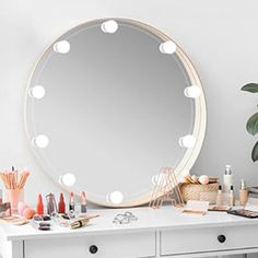 a vanity with an oval mirror and various makeup products on it