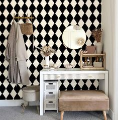 a dressing table with stool and mirror in front of a black and white checkered wall