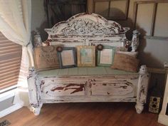 an old white bench with books on it in a room that has wood floors and windows