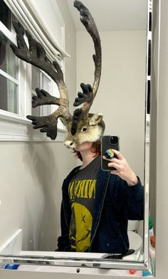 a man taking a selfie in front of a mirror with an antelope head