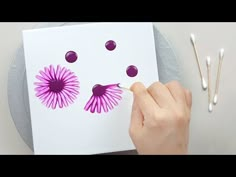 someone is drawing on paper with purple flowers