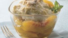 a dessert in a glass bowl on a white table cloth with a fork next to it