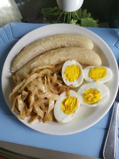 a white plate topped with an egg, banana and sliced up onion next to two hard boiled eggs