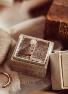 an engagement ring sitting in a box next to some other jewelry items on a table