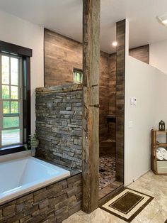 a bathroom with a stone wall and large tub next to a window in the corner