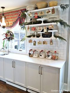 a kitchen with white cabinets and shelves filled with christmas decorations