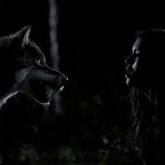 a woman with her mouth open next to a wolf in the dark, looking at it's teeth