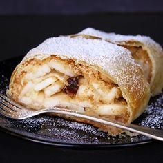 a piece of food on a plate with a fork next to it and powdered sugar