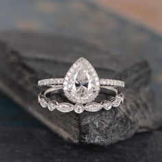 an engagement ring with a pear shaped diamond in the center on top of a rock