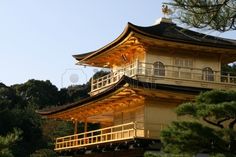 a tall wooden building with a balcony on top of it's roof and trees in the background