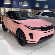 a pink land rover is on display in a showroom with other cars behind it