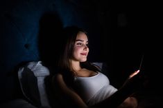 a woman sitting in bed looking at her tablet