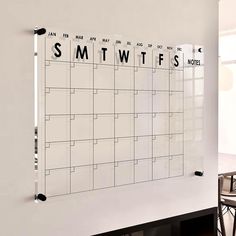 a white wall with a black and white calendar hanging on it's side next to a dining room table