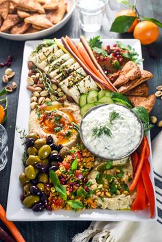 a platter filled with vegetables, meats and dip surrounded by other foodstuffs