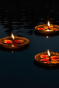 three candles floating on top of a body of water