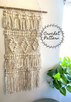 the wall hanging is made out of yarn and has fringes on it, along with a potted plant