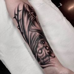 a bat tattoo on the left arm and leg, with an owl in it's mouth