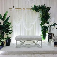 a white bench sitting in front of a window next to potted plants and other decorations