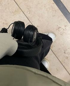 a pair of black headphones sitting on top of a person's leg in front of a tile floor