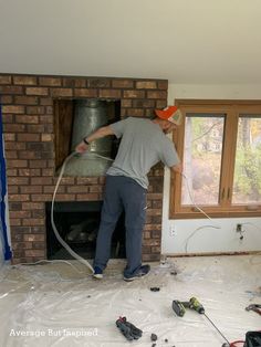 a man is working on a brick fireplace with a blow dryer in his hand